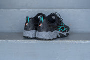 black asics with teal and grey accents on a set of stairs